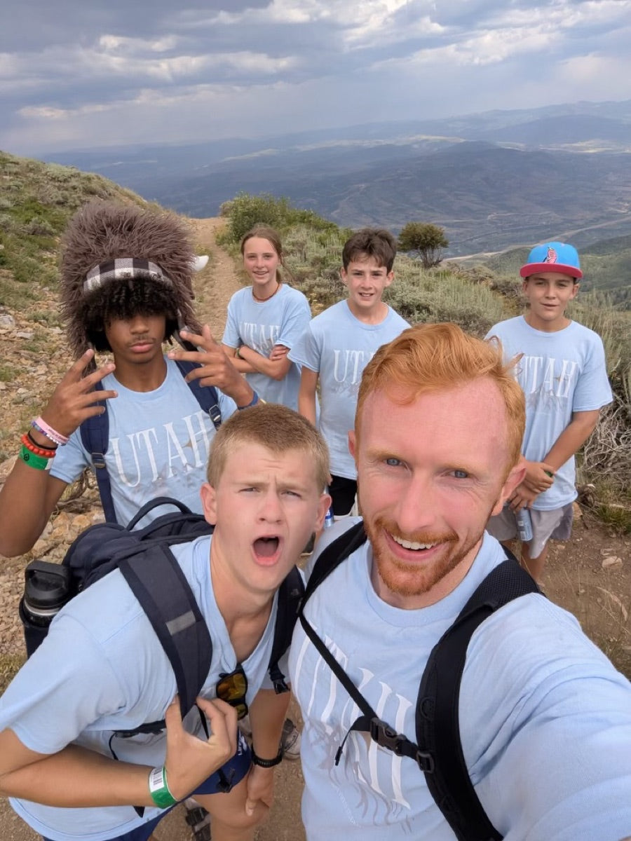 Students and a leader on a mountain trail in light blue Utah tees