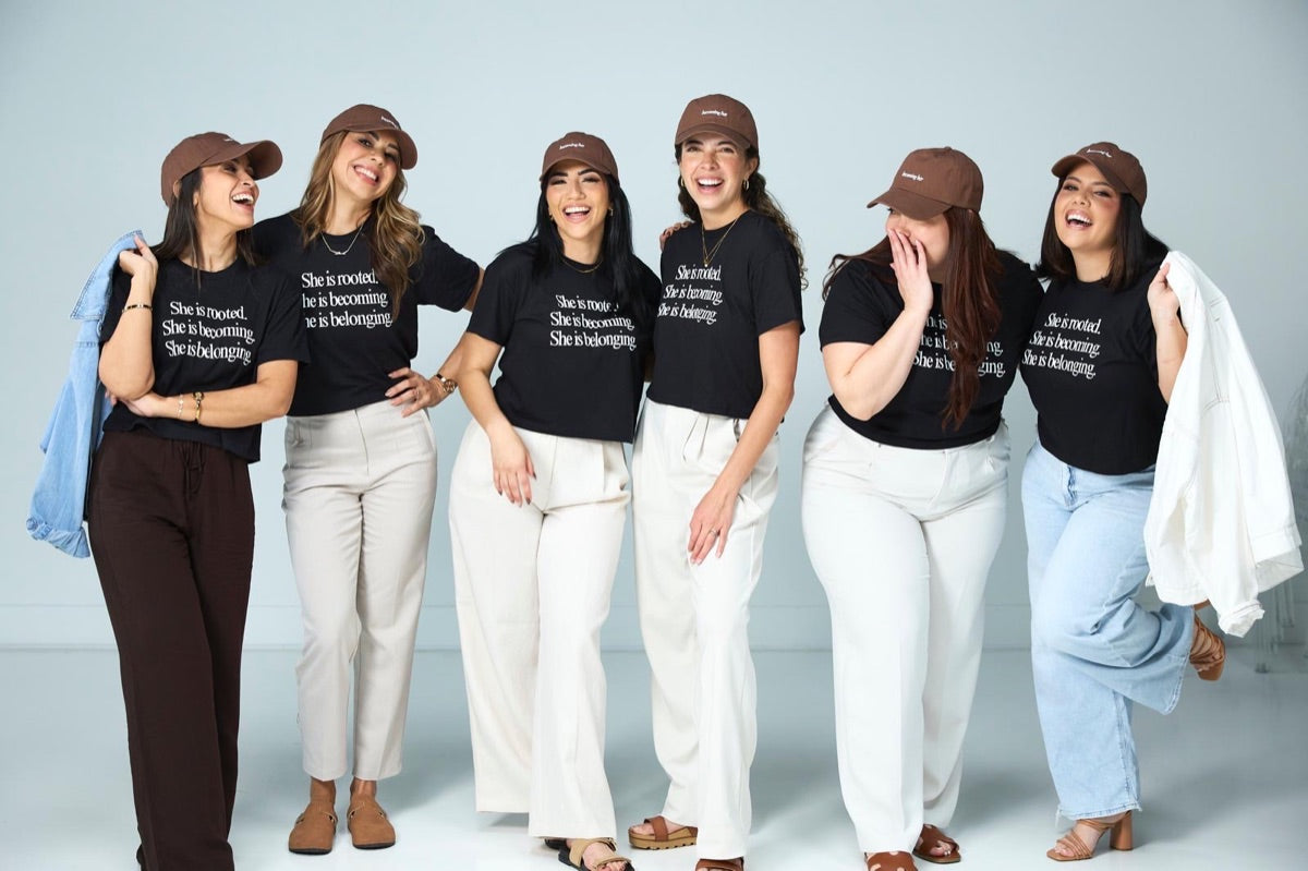 Six women in She Is Rooted tees and brown caps